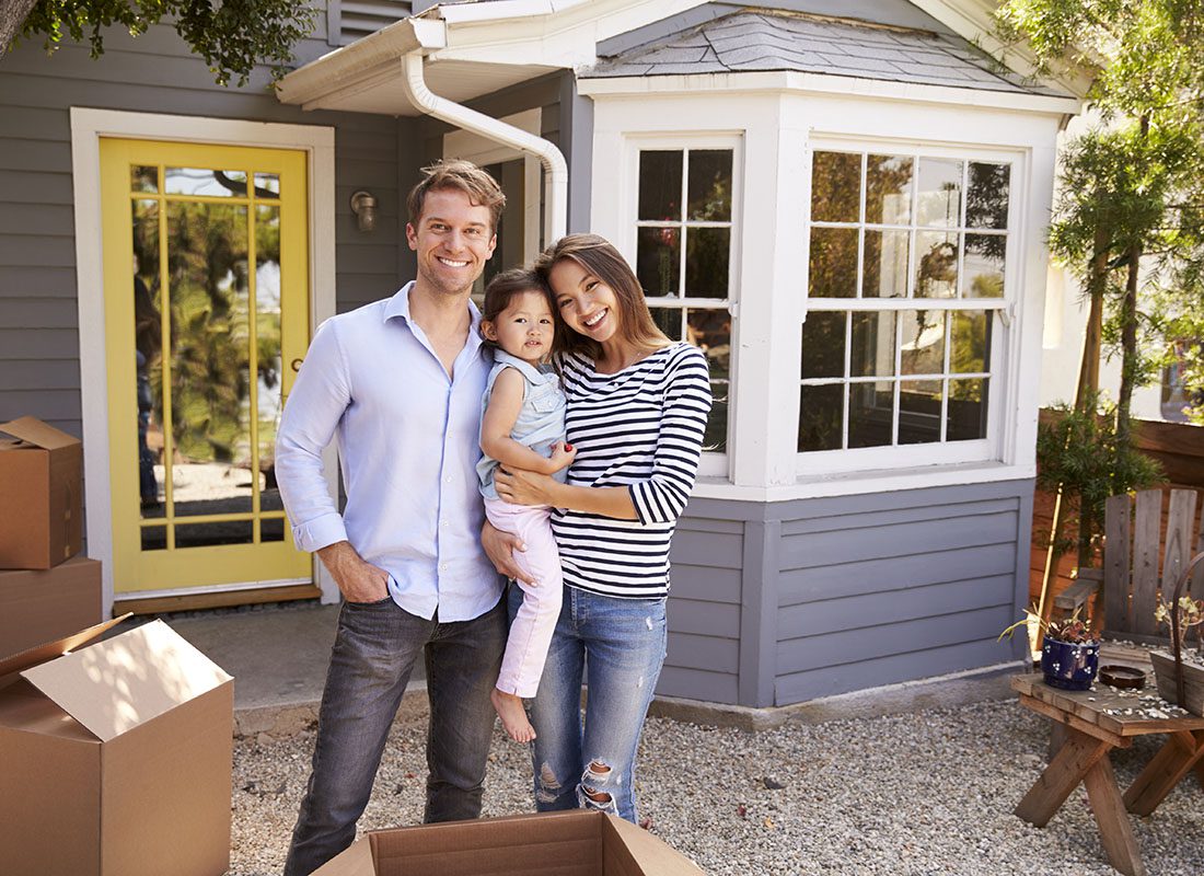 Personal Insurance - Portrait of a Young Family with a Daughter Standing Outside Their New Home on Moving Day